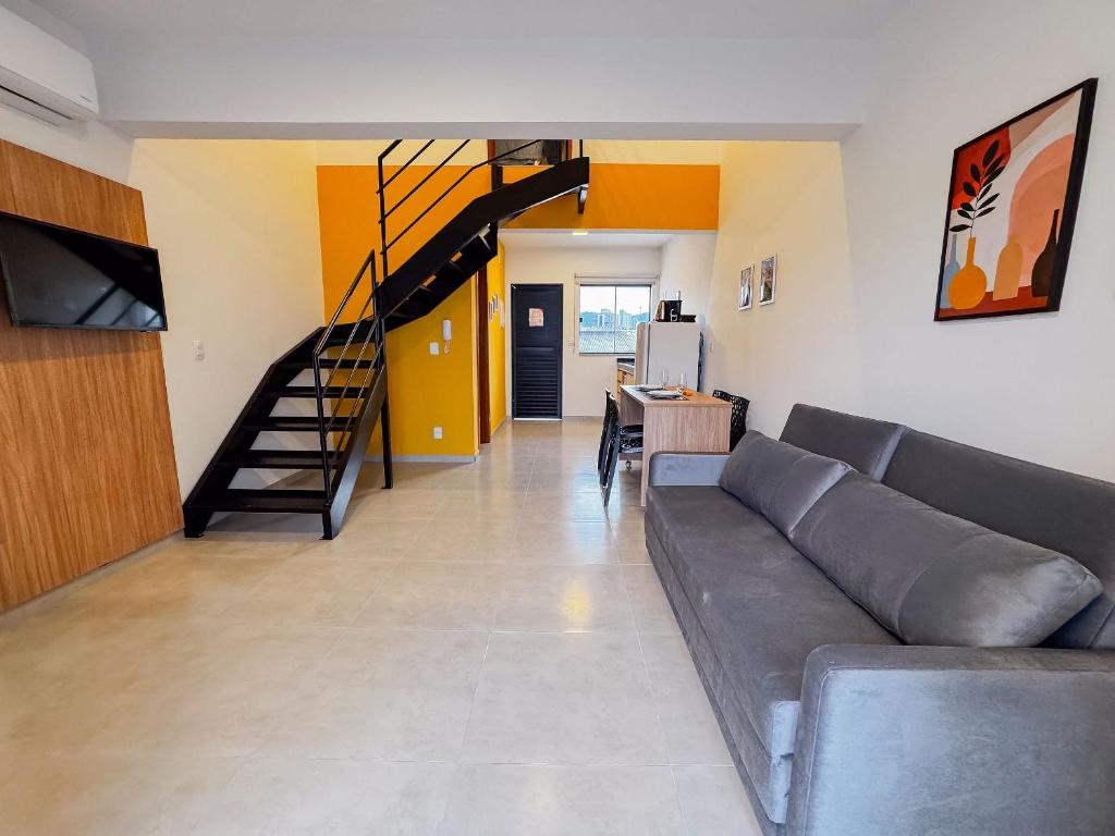 a living room with a couch and a staircase at Centro: Flat p/ 4 pessoas + Vaga in Brusque