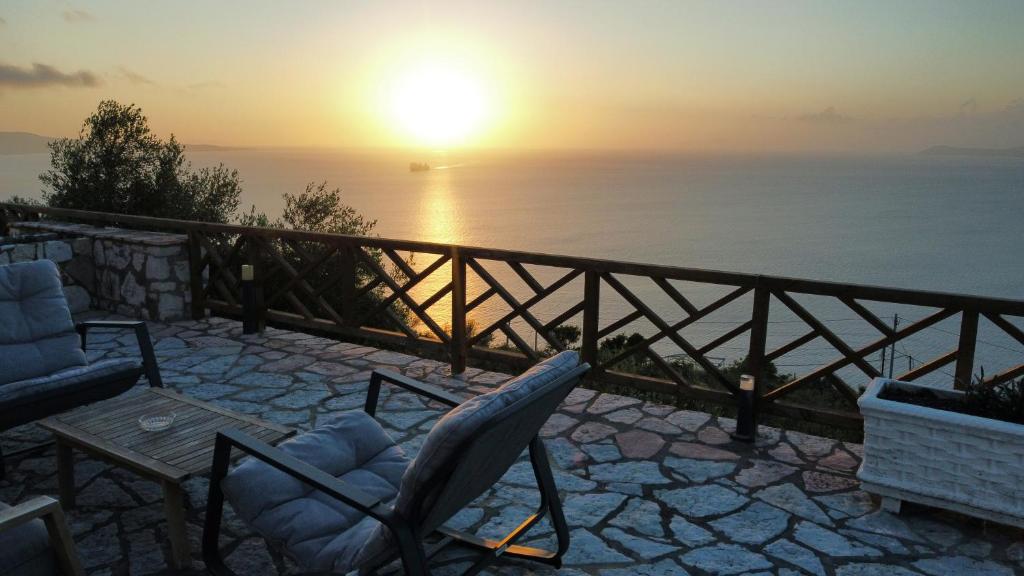 a sunset over the ocean with two chairs and a table at Luxury Pigeons Cave Suites in Ksamil