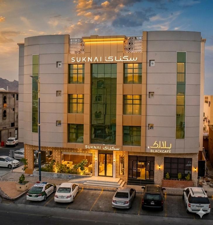 a building with cars parked in a parking lot at سكناي صلاح الدين للشقق المخدومة - Suknai Salah Aldin Serviced Apartments in Hail