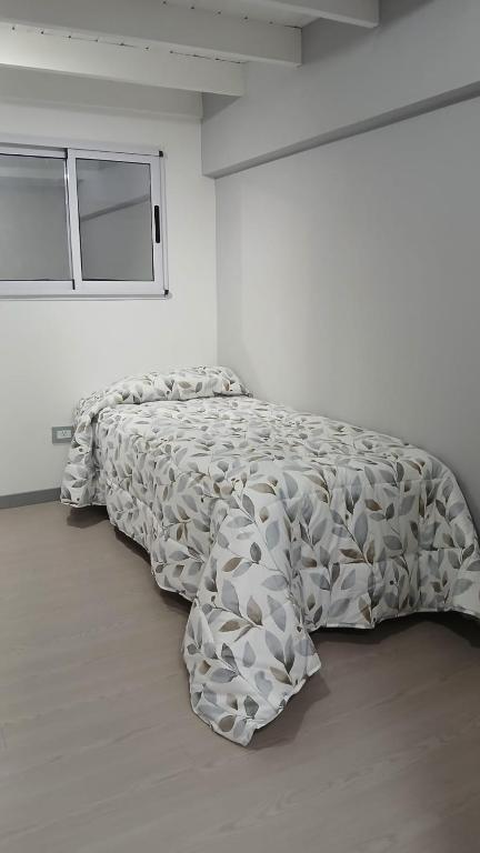 a bedroom with a bed with a comforter on it at Hospedaje DUDOMU in Buenos Aires