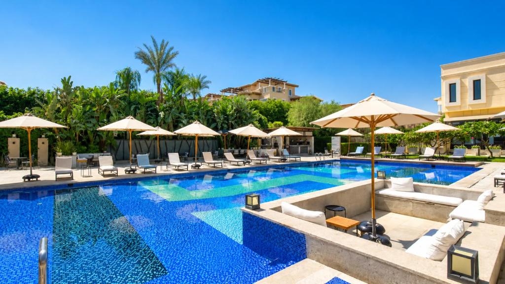 a pool with chairs and umbrellas at a resort at Elegant Hydepark Apt With Garden in New cairo