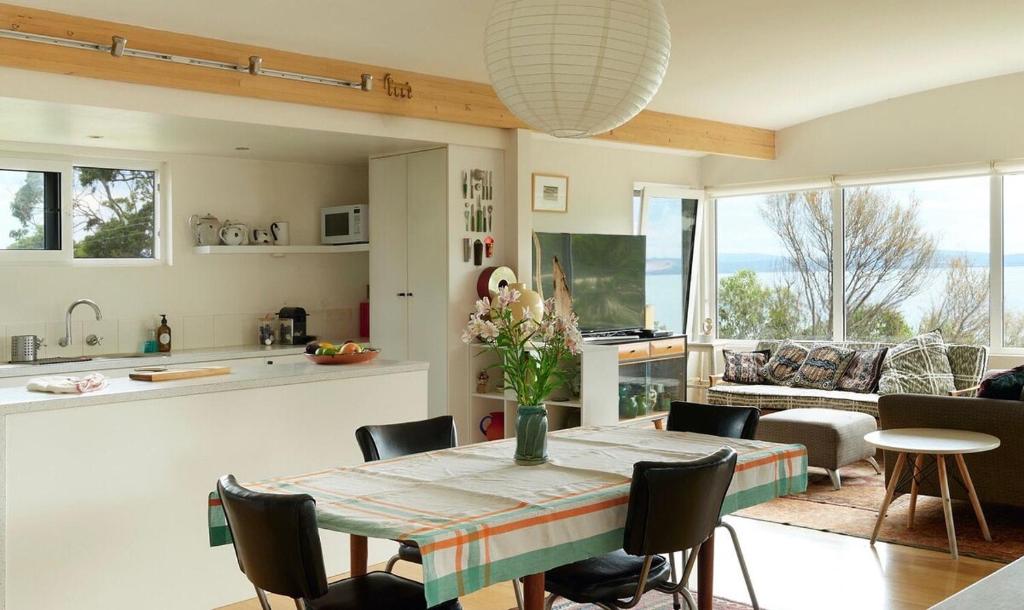 a kitchen and living room with a table and chairs at Artist's Beach House - Waterfront in Murdunna