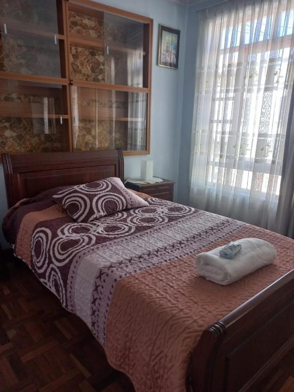 a bed with a red and white blanket and a window at Casa Zudañes in Sucre