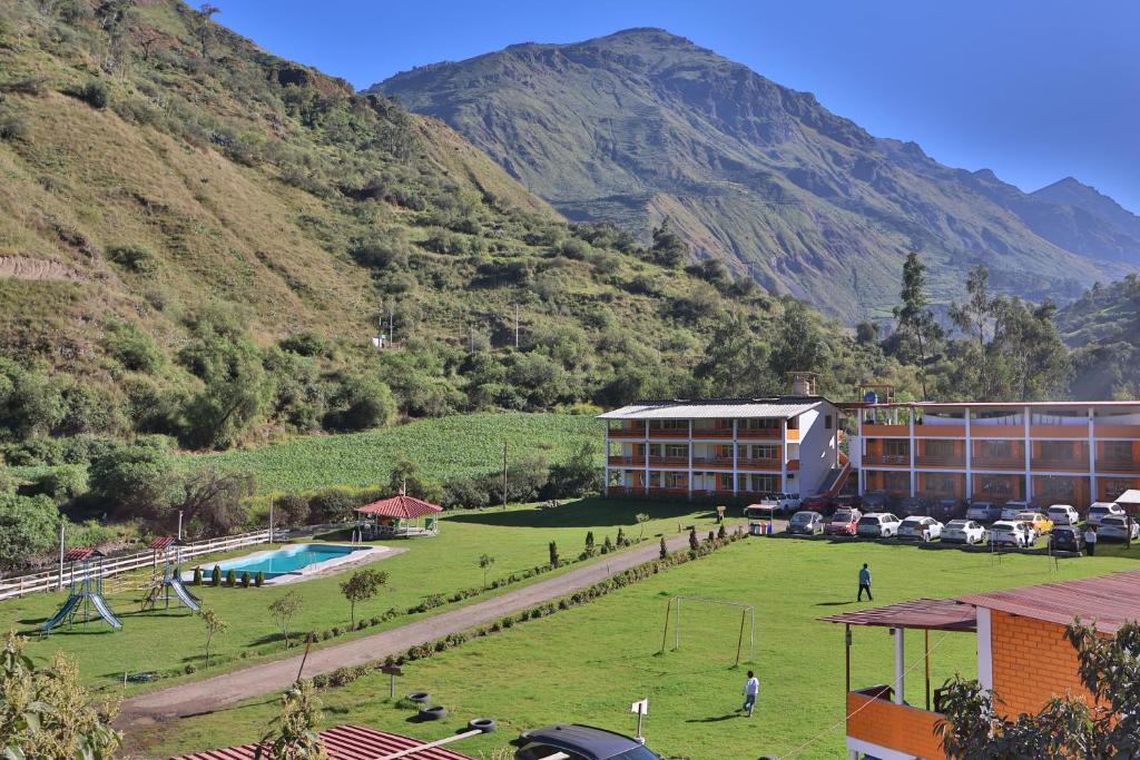 a resort with a large field and mountains in the background at Tambo Lodge Canta in Canta