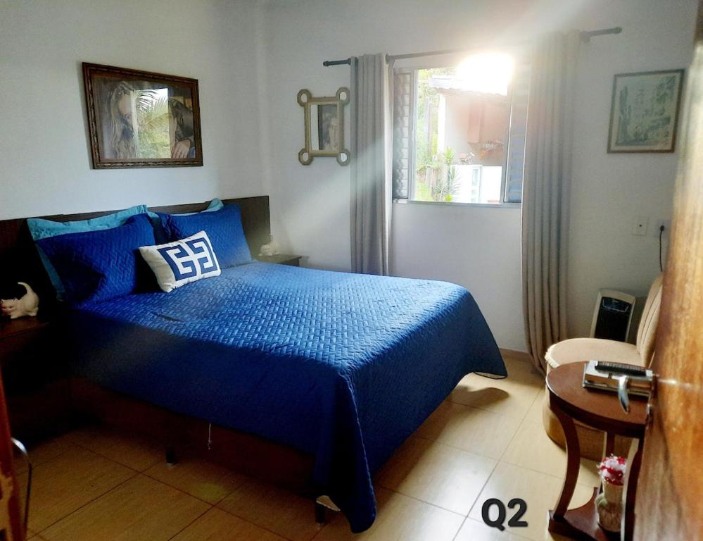 a bedroom with a blue bed and a window at Linda Chácara Próxima a Monte Verde in Camanducaia
