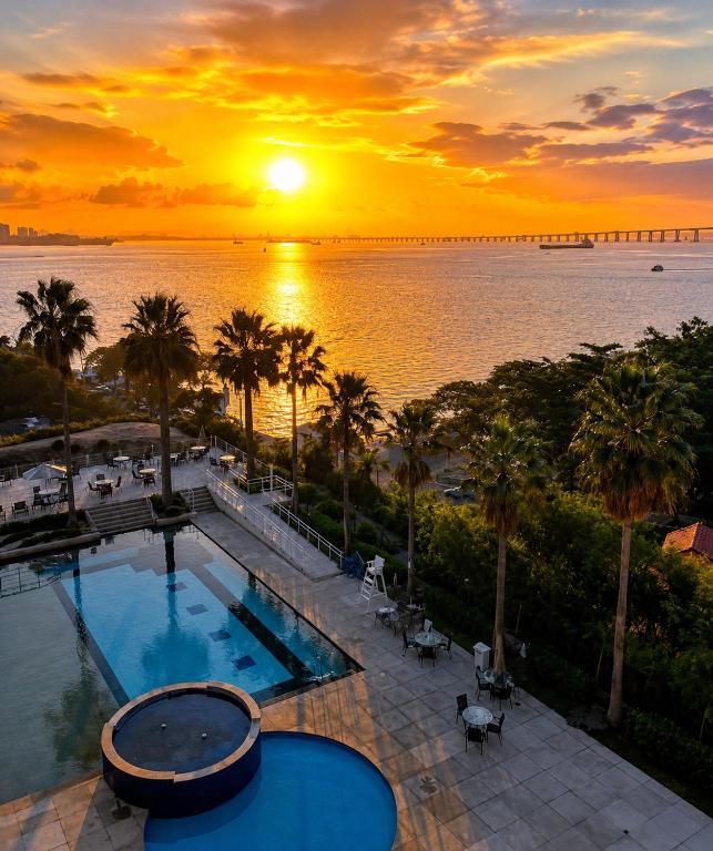 a view of a pool with a sunset in the background at Apartamento Vista Ponte in Niterói