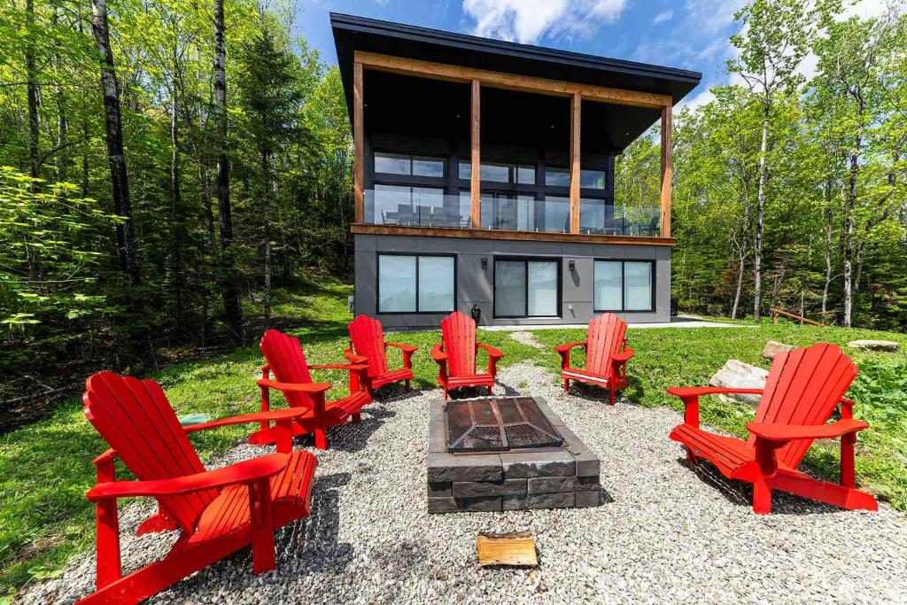 a group of red chairs in front of a house at Käbane OPeak - Mezzanine sur le Fleuve in Les Éboulements