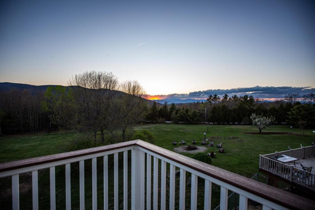 a view of a yard from a balcony with the sun setting at Beautiful Bridgton Apartment in Bridgton