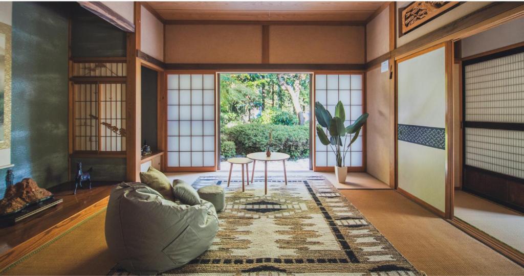 a living room with a couch and a table at 最大8名 庭園に住むアート Active Art Hotel 80畳の広さを誇る古民家 日本庭園を独り占め in Sado