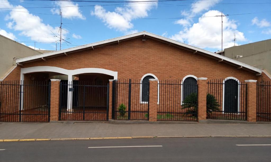 a red brick building with a black fence at Casa Próxima ao Parque do Peão in Barretos