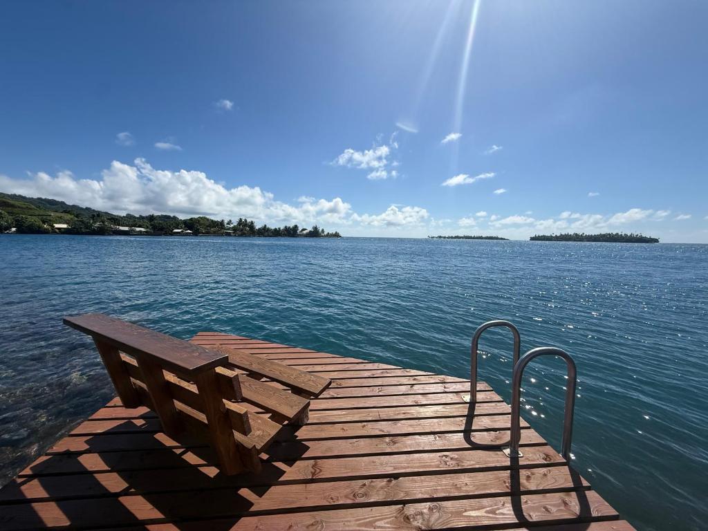 a wooden dock with a bench on the water at Fare Holidays - Raiatea in Taputapuapea