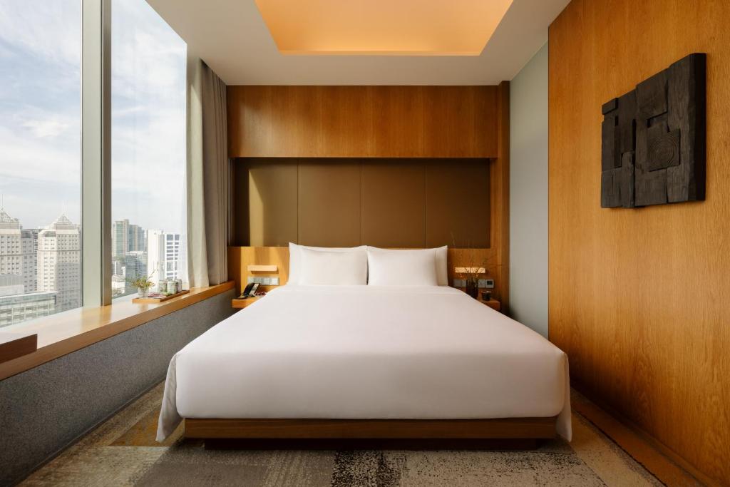 a bedroom with a large bed and a large window at Oasia Hotel Novena, Singapore by Far East Hospitality in Singapore