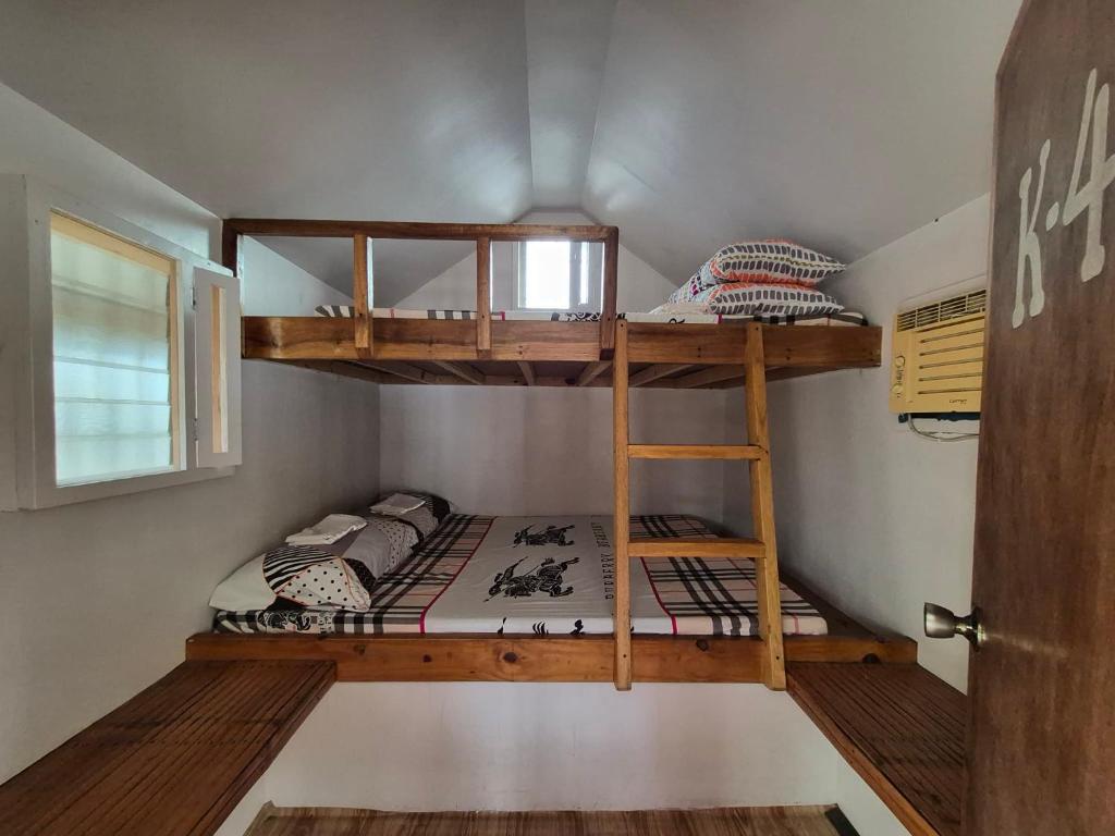 two bunk beds in a small room with a door at Beachfront Aircon Kubo for 4pax in Caba