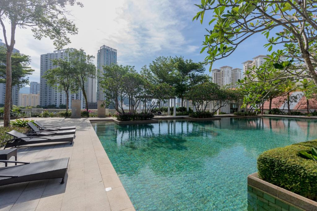a swimming pool with lounge chairs and trees in a city at Straits Quay Waterside Penang in Tanjong Tokong