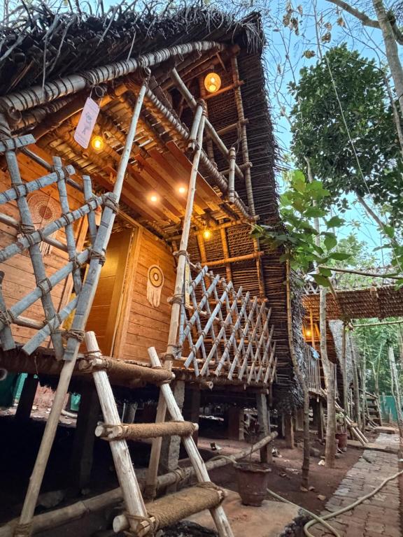 a bamboo house with a bench in front of it at v kudil in Auroville
