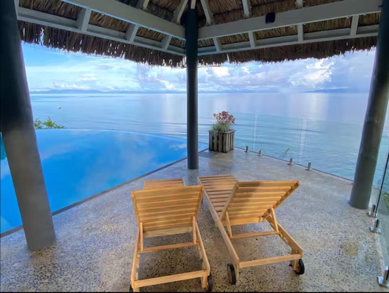 two chairs sitting under an umbrella next to the water at Raitotoka Eco Resort in Matei