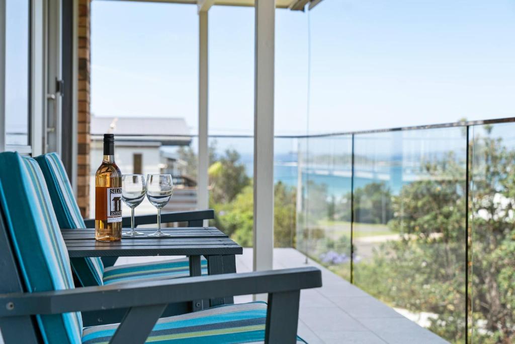 a table with two glasses of wine on a balcony at Sea Breaks Escape Manyana in Manyana
