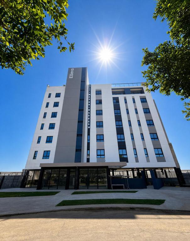 a tall white building with the sun in the sky at Hotel In Loft Elleva Studio in Sinop