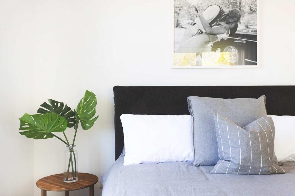 a bedroom with a bed with a vase on a table at Mollymook Delight - with easy ocean & golf access in Mollymook