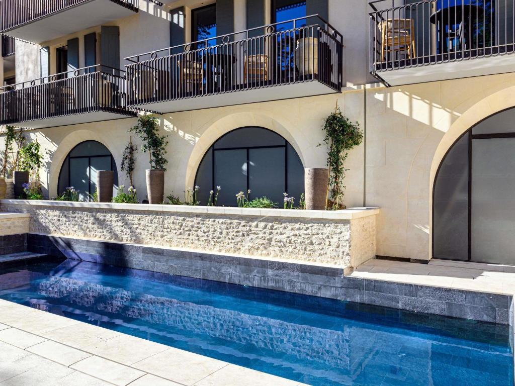 a house with a swimming pool in front of a building at L'Isle de Leos Hotel & Spa - MGallery Collection in L'Isle-sur-la-Sorgue