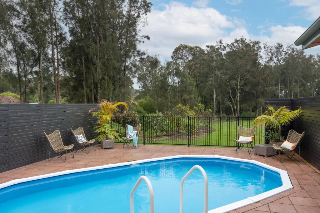 a swimming pool with chairs and a fence at Banyula in Bawley in Bawley Point