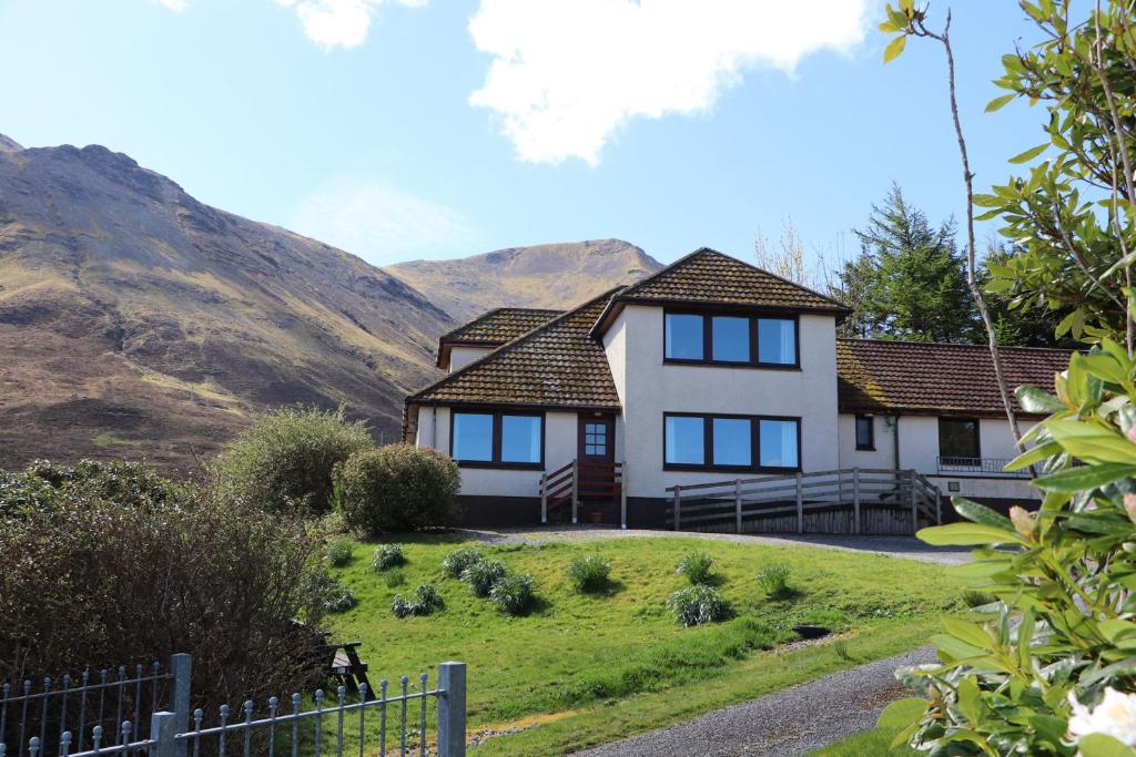a house on a hill with mountains in the background at MacKenzies Peak in Sconser
