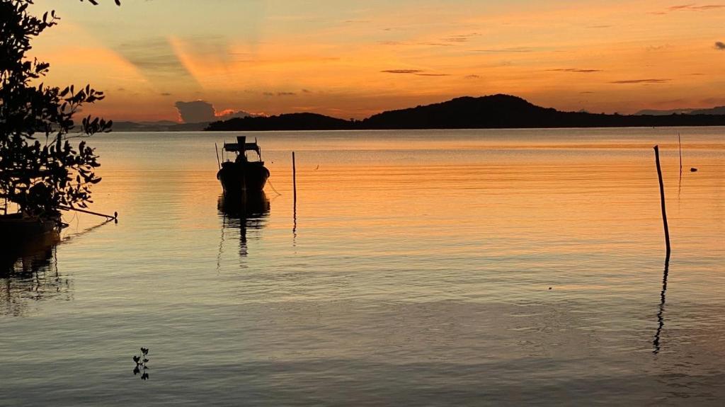 a boat sitting in the water at sunset at Deep House Sea View in Ko Lanta