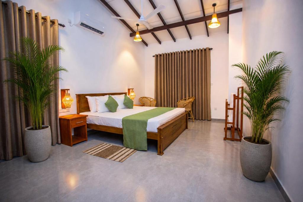 a bedroom with a bed and two potted plants at The Clouds Ahangama in Ahangama