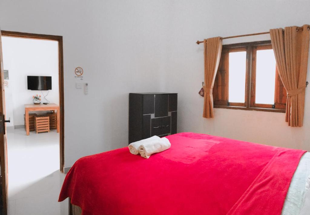 a bedroom with a bed with a red blanket at Anorawi Surf accommodation in Maluk