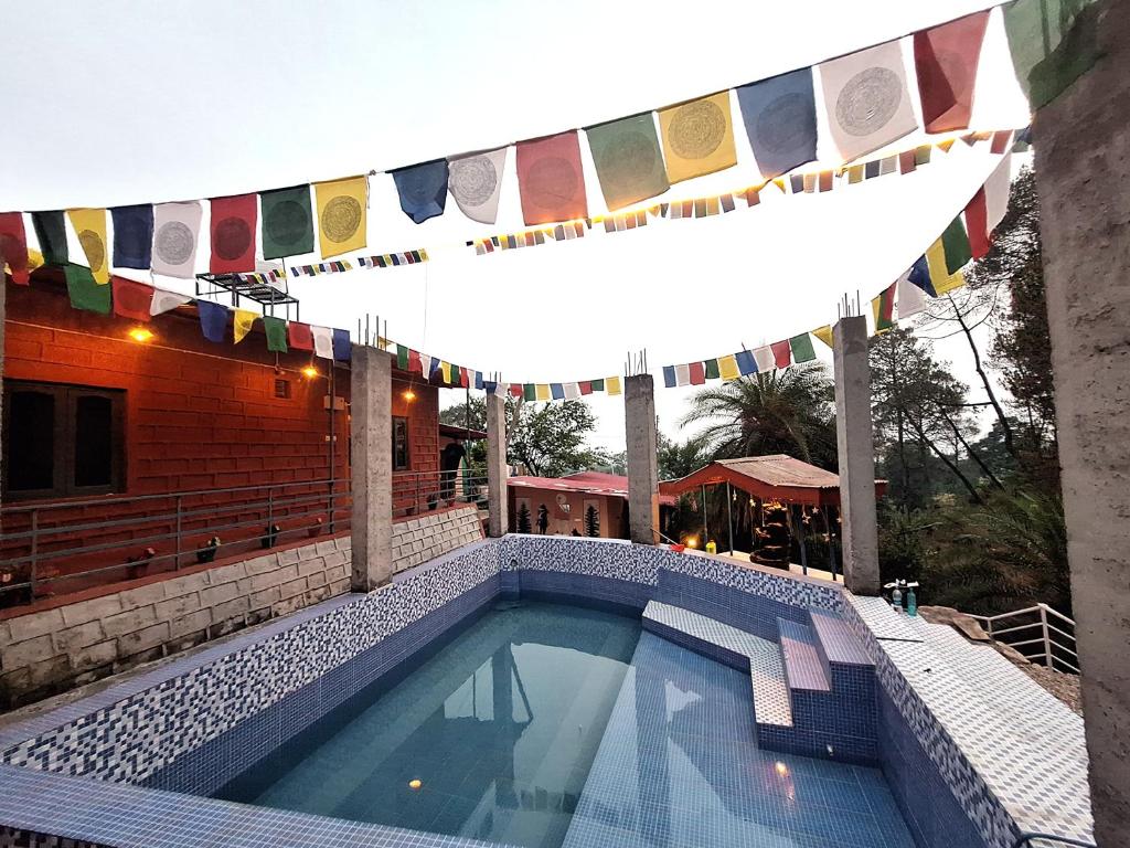 a swimming pool with flags hanging above it at TATHASTU RETREAT BiR -TRB in Bīr