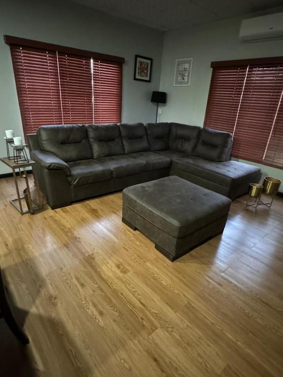 a living room with a leather couch and wooden floors at Casa No6 Ascot in Carapo