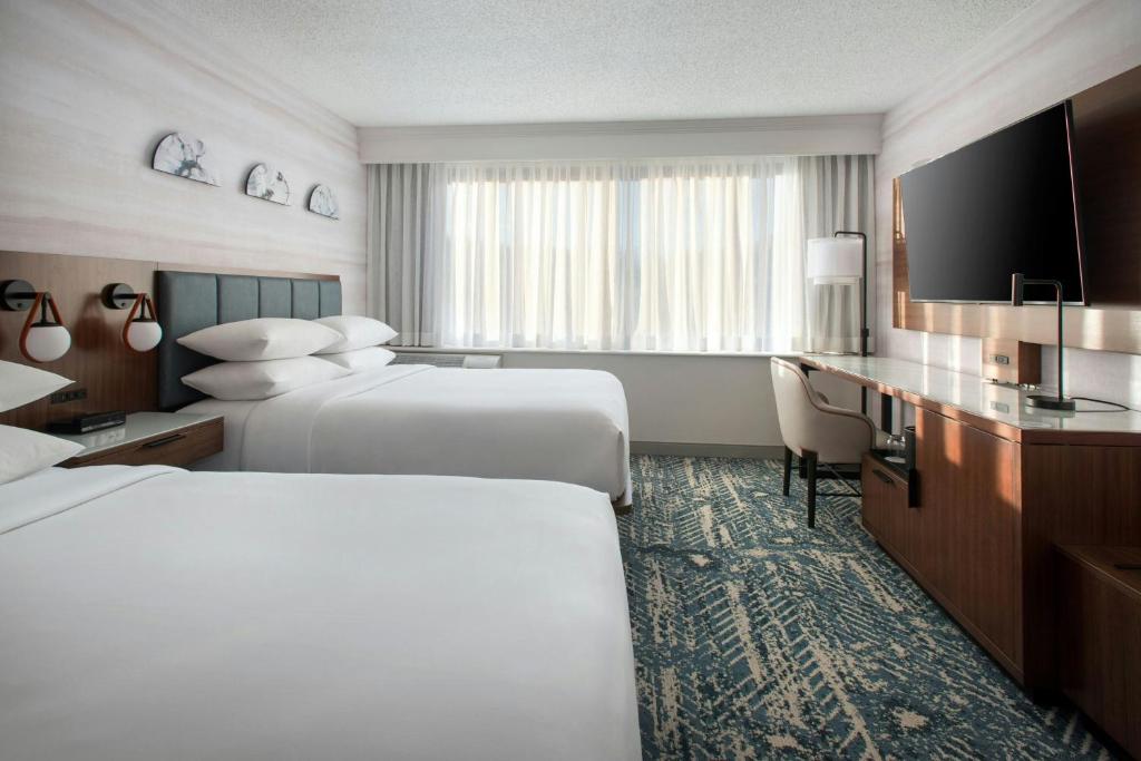 a hotel room with two beds and a flat screen tv at Boston Marriott Peabody in Peabody
