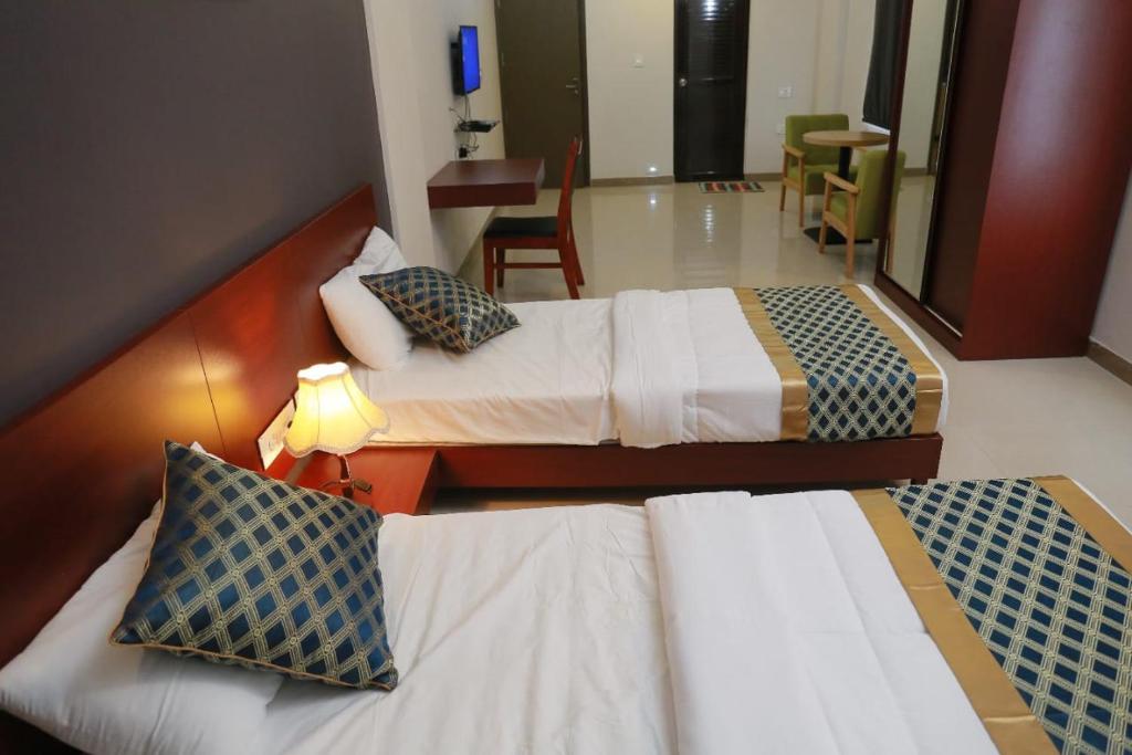 a hotel room with two beds and a table at Peace Residency in Jāmb
