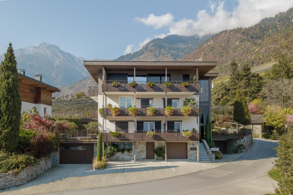 a house with a balcony and mountains in the background at Ferienwohnungen Steinegg in Lagundo