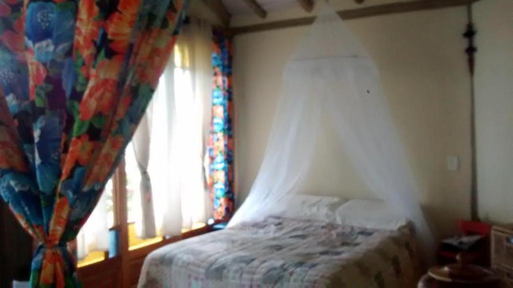 um quarto com uma cama com uma cortina e uma janela em Bangalô da Mata em Ilhabela