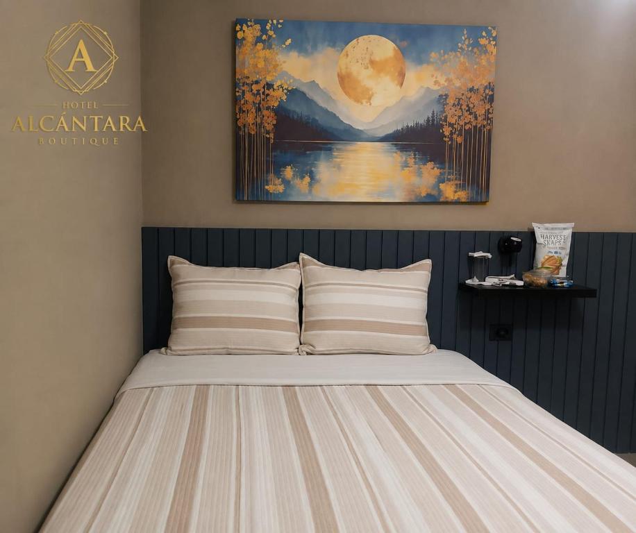 a bed in a bedroom with a painting on the wall at Hotel Alcántara Boutique in San Salvador