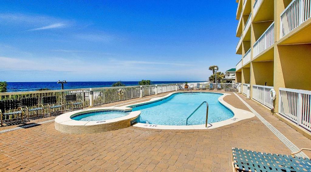 a swimming pool in front of a building with the ocean at Seychelles Resort by Panhandle Getaways in Panama City Beach