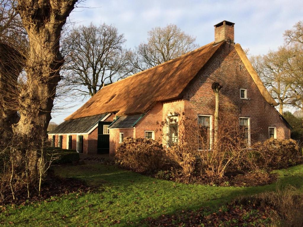 an old brick house with a thatched roof at Het Schepershoes in Peest