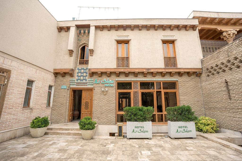 a building with two potted plants in front of it at As-Salam Boutique Hotel in Bukhara