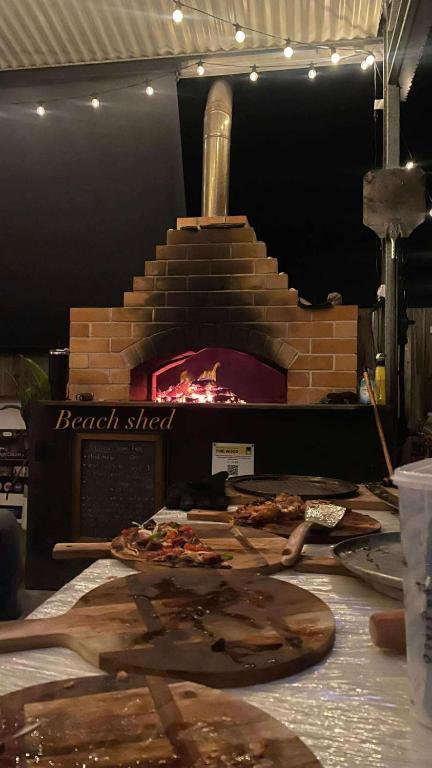 a brick oven with a pizza on a table at Beach Shed with Pizza Oven in Toogoom