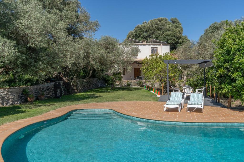 a swimming pool with two lounge chairs and a house at Cortijo Corral del Gallo in Órgiva