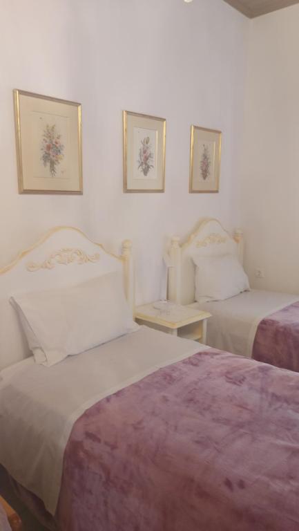a bedroom with two beds and two pictures on the wall at Nineta's House Sea View near the Airport in Artemida