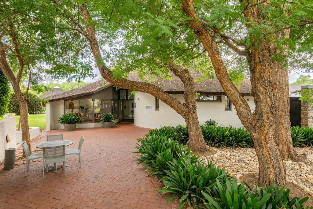 a patio with a table and chairs in front of a house at Protea Hotel by Marriott Oudtshoorn Riempie Estate in Oudtshoorn