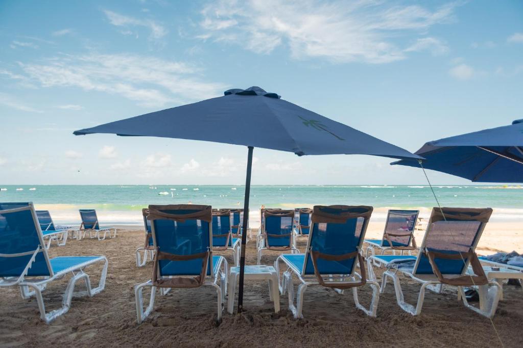 een groep stoelen en een parasol op het strand bij OCEAN VIEW DELUXE SUITE: PVT. BEACH & POOL in San Juan