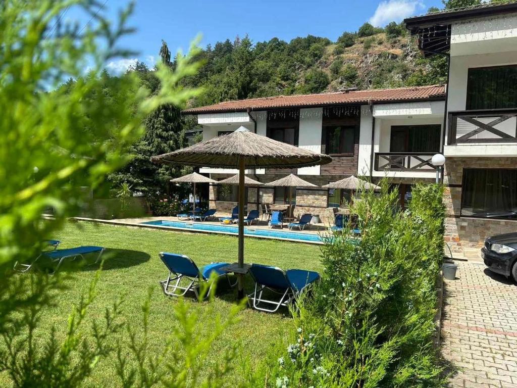 a yard with chairs and an umbrella and a pool at Relax Houses in Ognyanovo