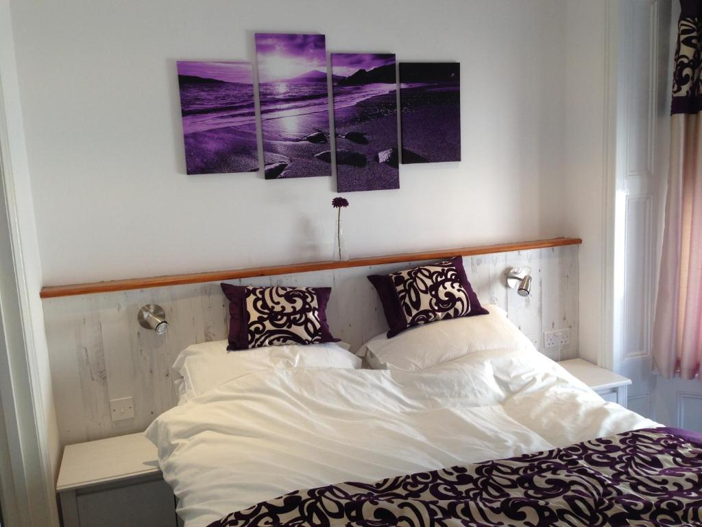a bedroom with a bed with three paintings on the wall at Ocean House - Weymouth in Weymouth