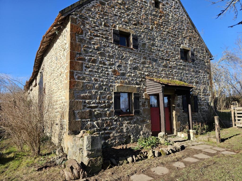 an old stone building with a red door at authentieke gite Mouton in Les Vignolats
