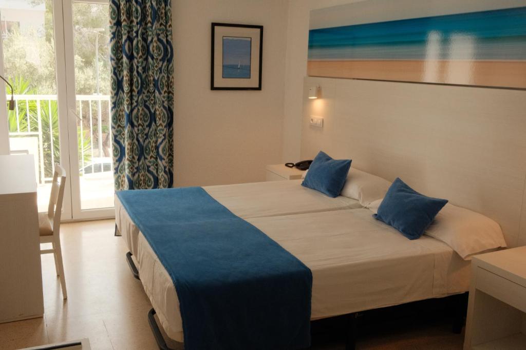 a hotel room with a large bed with blue pillows at Hotel Cassandra in El Arenal