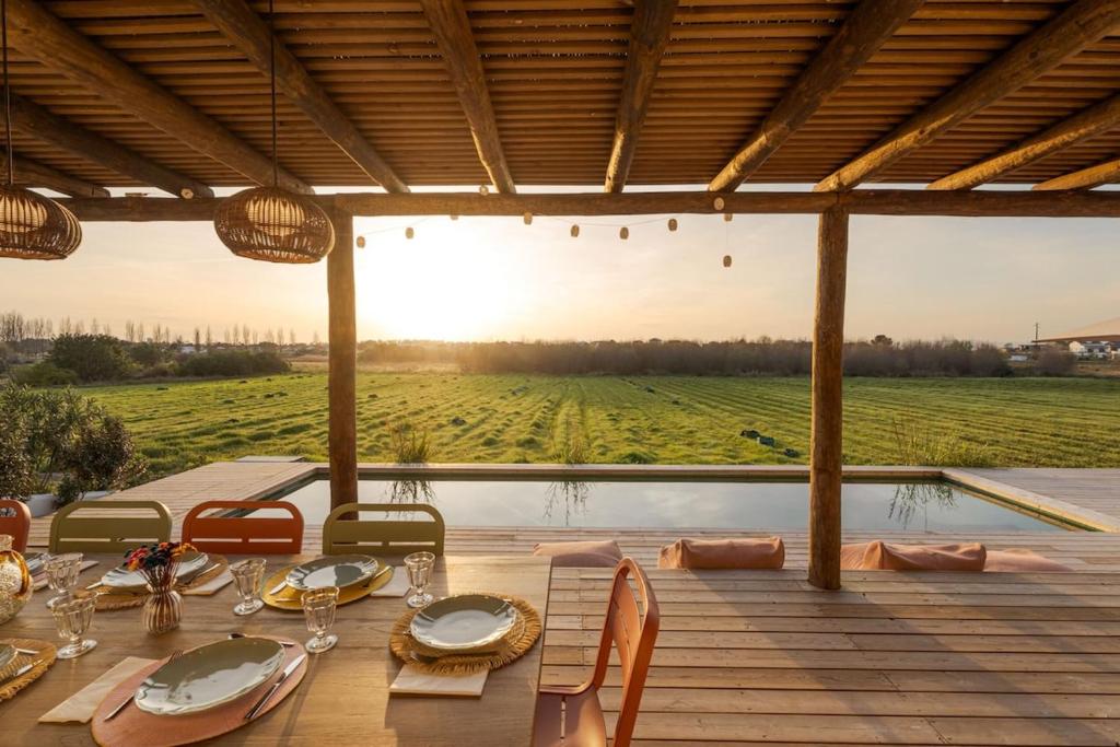a table with chairs and a view of a field at Casa Terracotta with Private Pool in Comporta