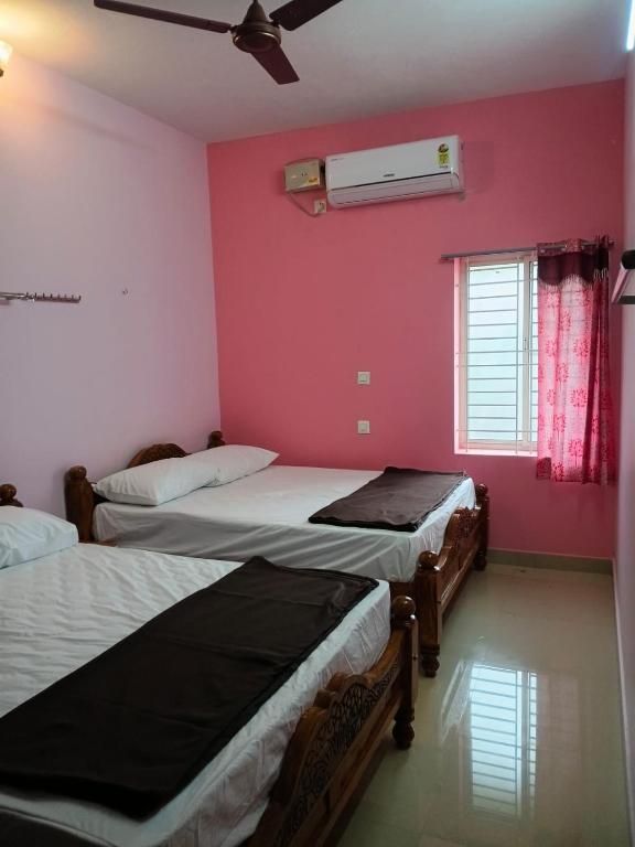 three beds in a room with a pink wall at Vihaasam Homestay in Thanjāvūr